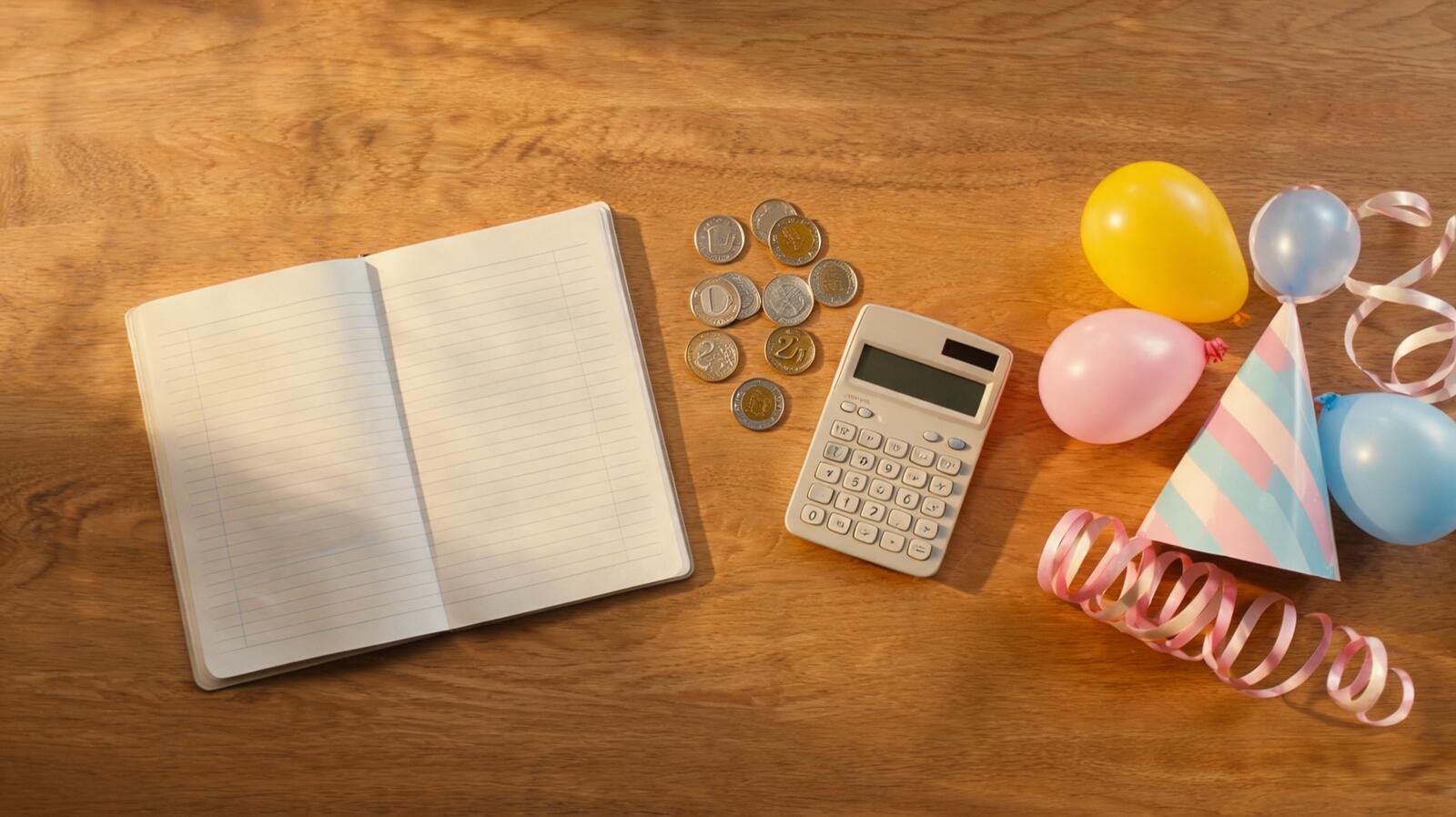 Carnet de budget, calculatrice et fournitures de fête sur une table en bois